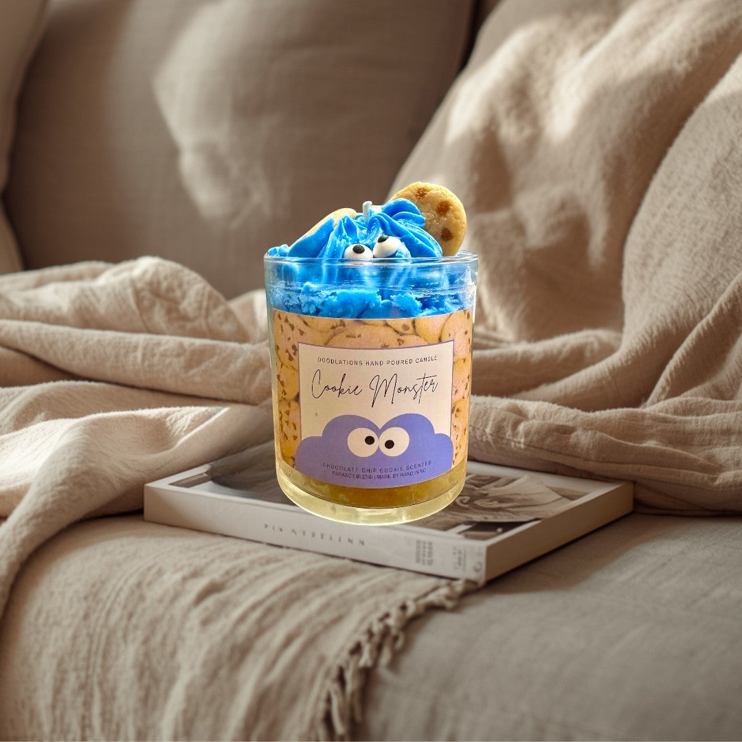 Doodlations Coffee Bar & Boutique Cookie Monster candle with blue frosting, candy eyes, and cookie accents. Chocolate chip cookie scented.