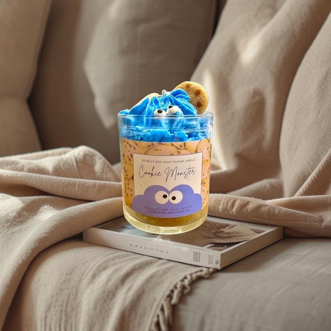 Doodlations Coffee Bar & Boutique Cookie Monster candle with blue frosting, candy eyes, and cookie accents. Chocolate chip cookie scented.