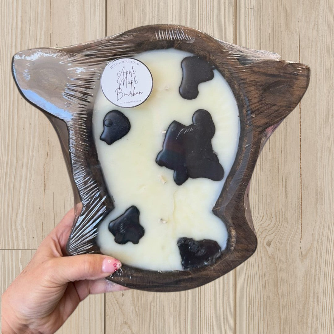Doodlations Coffee Bar & Boutique Apple Maple Bourbon cow head dough bowl candle with black spots, made of wood and wax.