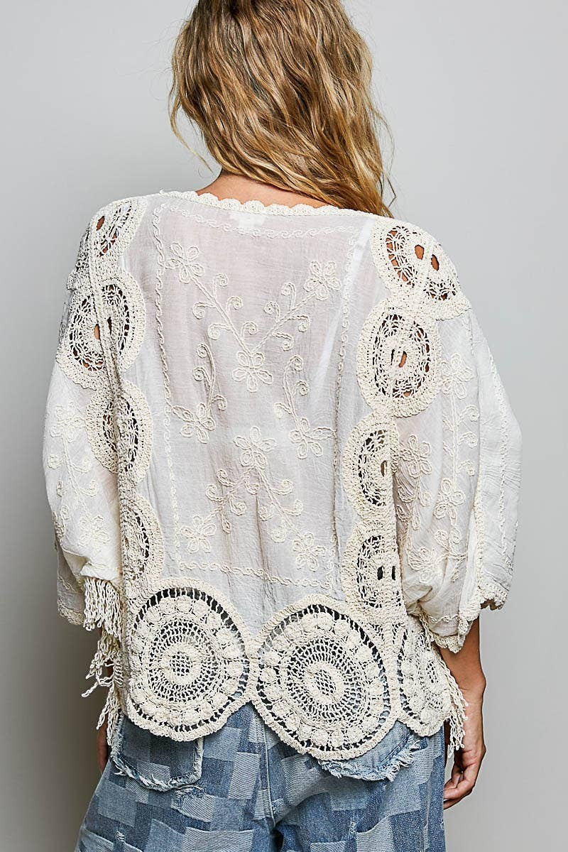Back view of Doodlations Coffee Bar & Boutique cream crochet top with floral embroidery and intricate knit patterns.