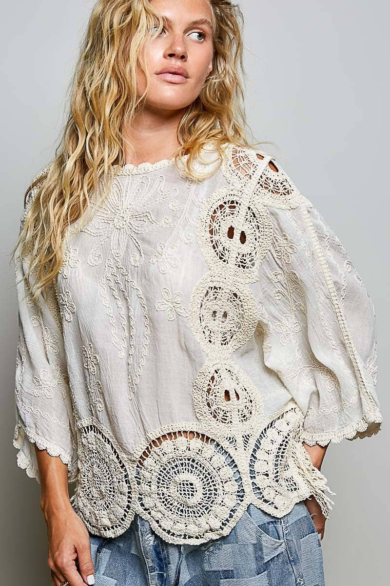Doodlations Coffee Bar & Boutique cream crochet top with floral embroidery, round neck, and roomy short sleeves.