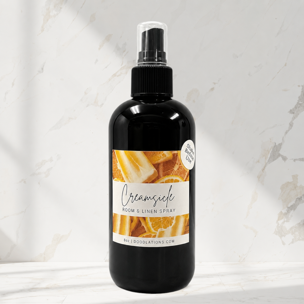 Doodlations Coffee Bar & Boutique Creamsicle room and linen spray in a black bottle with citrus fruit label design.