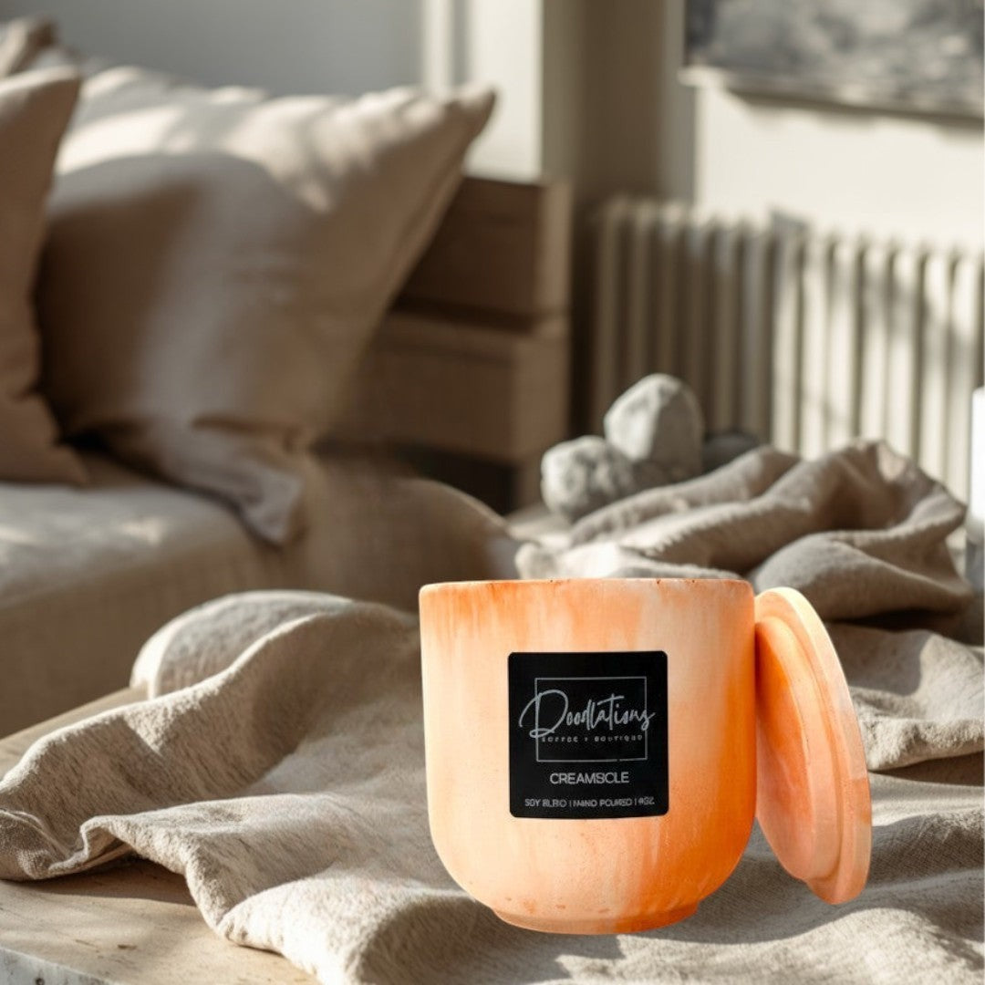 Doodlations Coffee Bar & Boutique Creamsicle marbled concrete candle with lid. Orange and white swirl pattern.
