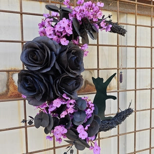 Doodlations Coffee Bar & Boutique crescent moon wreath with black roses, purple flowers, and a black cat silhouette.