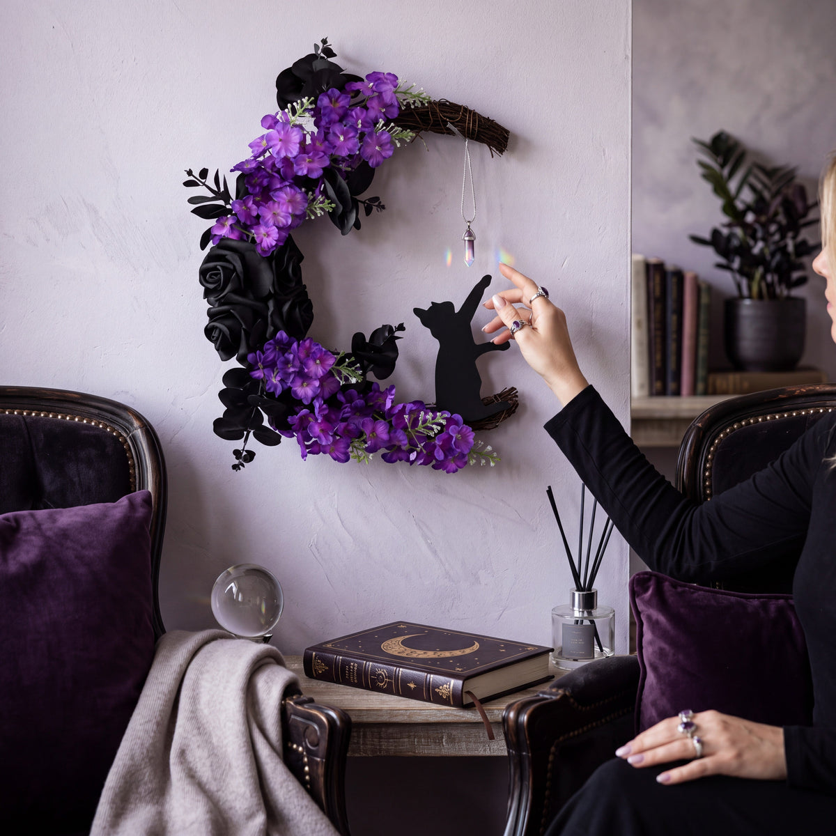 Doodlations Coffee Bar & Boutique crescent moon wreath with black roses, purple flowers, cat silhouette, and crystal.