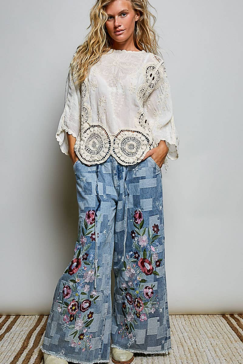 Doodlations Coffee Bar & Boutique white crochet top with floral embroidery and round neck worn with patchwork jeans