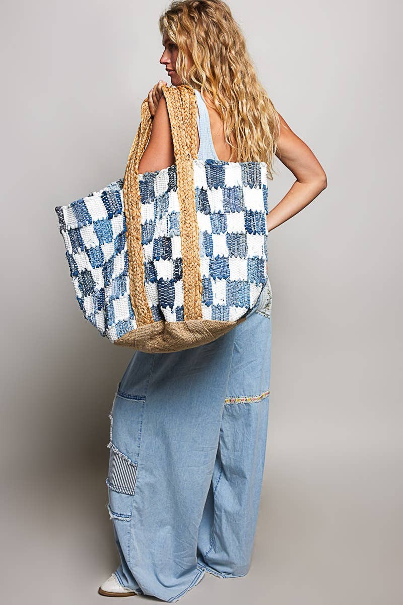 Doodlations Coffee Bar & Boutique ivory and blue denim checkerboard woven tote bag with straw handles on a model