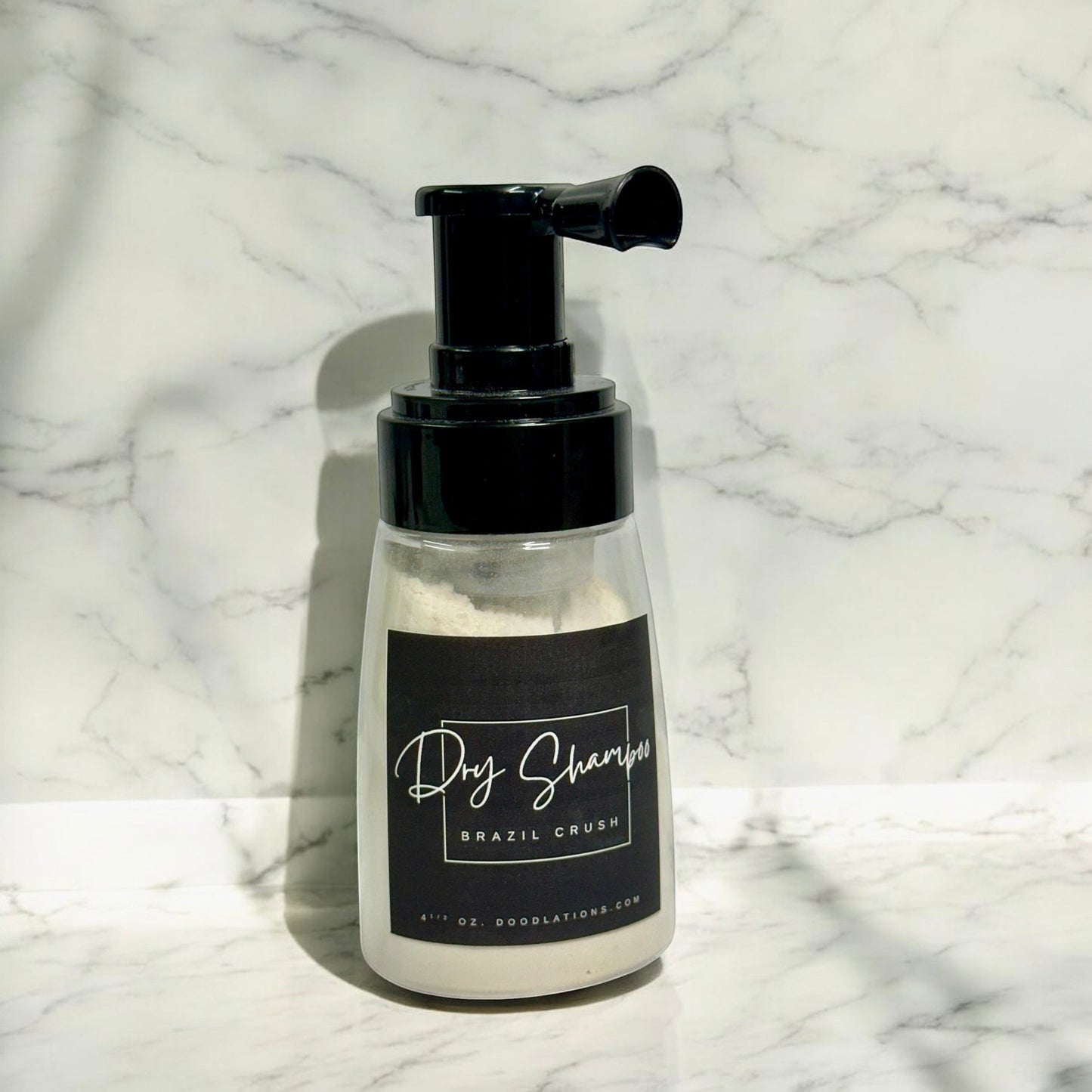 Doodlations Coffee Bar & Boutique dry powder shampoo in a clear pump bottle with a black label on a marble background.