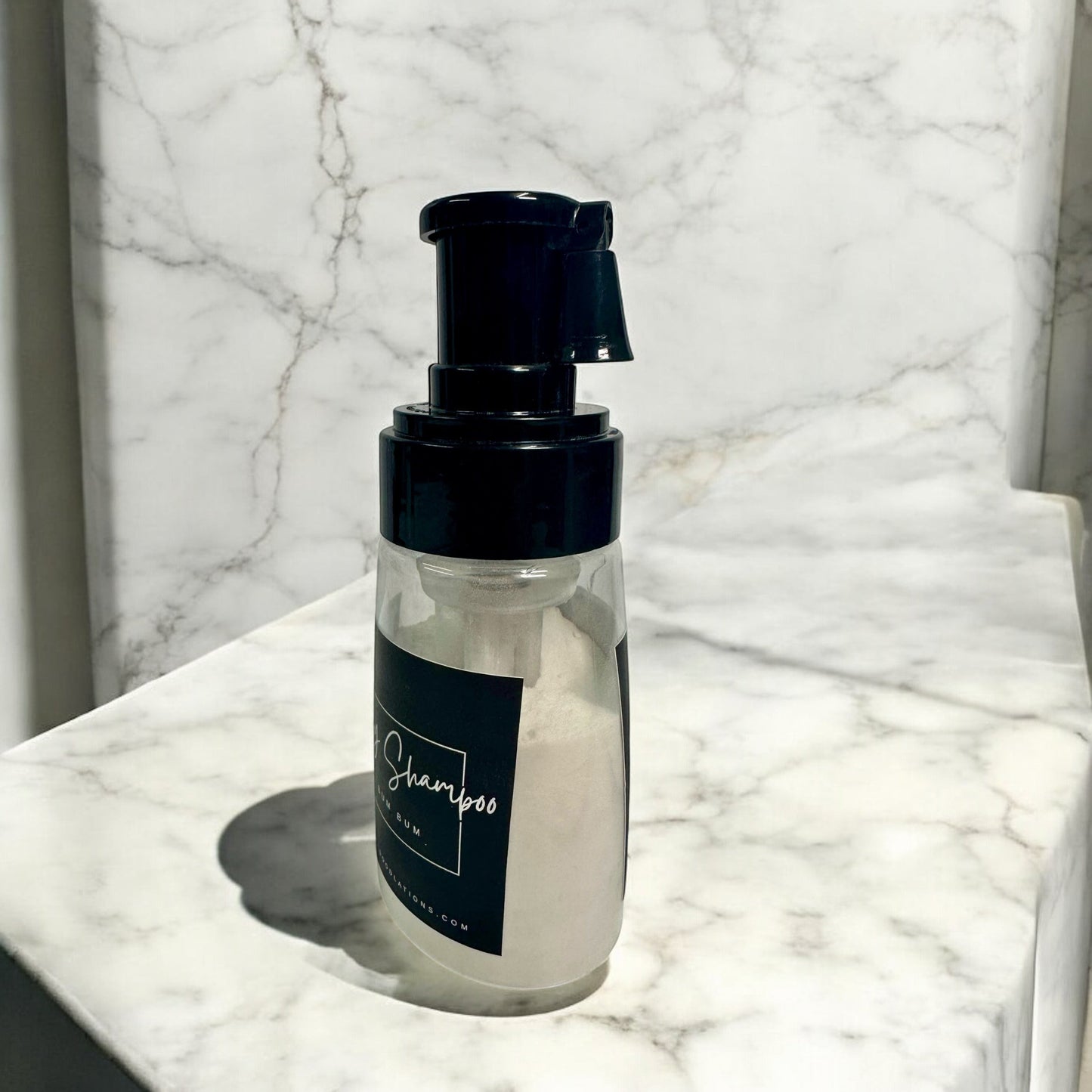 Doodlations Coffee Bar & Boutique The Narcissist dry powder shampoo in a clear bottle with a black pump dispenser.