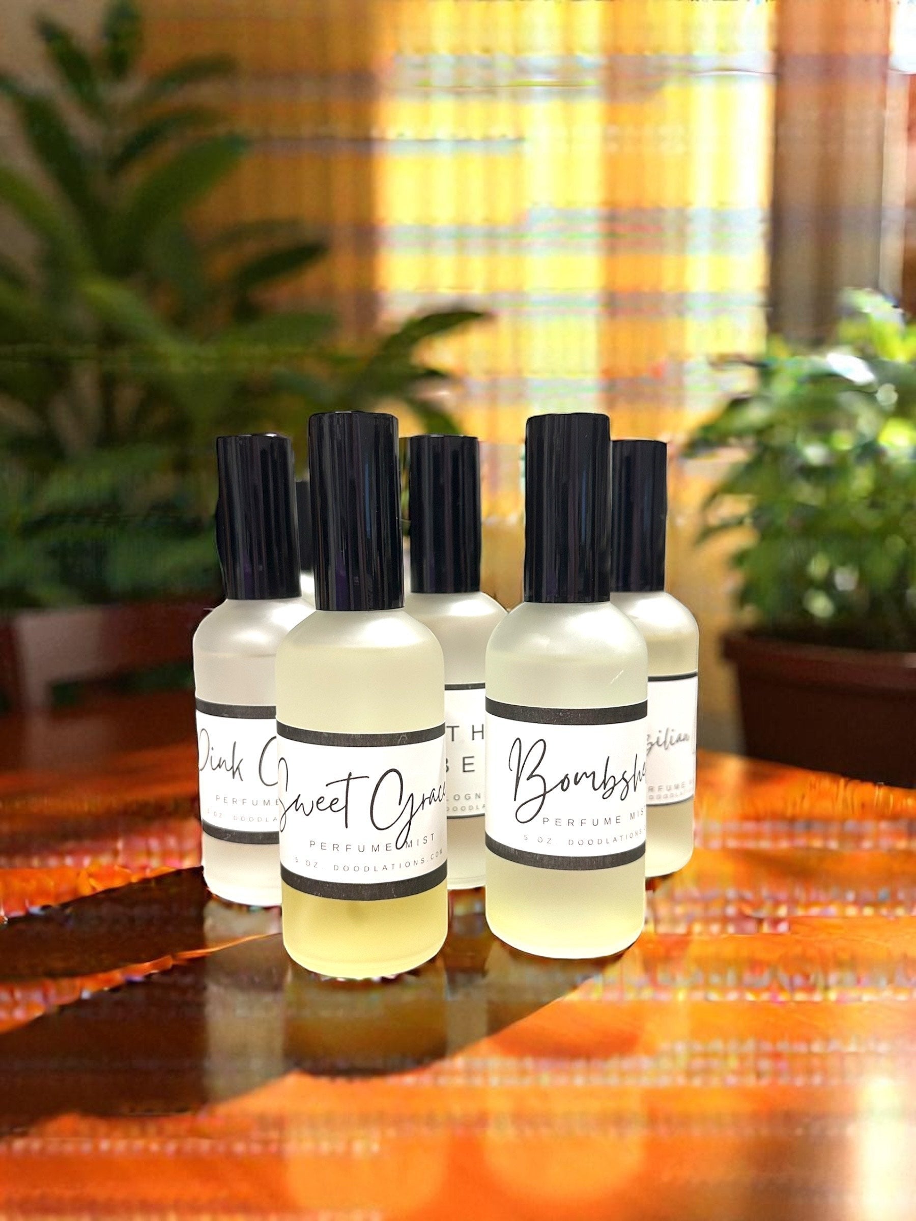 Doodlations Coffee Bar & Boutique collection of luxury fine mist perfume bottles with black caps on a wooden table.