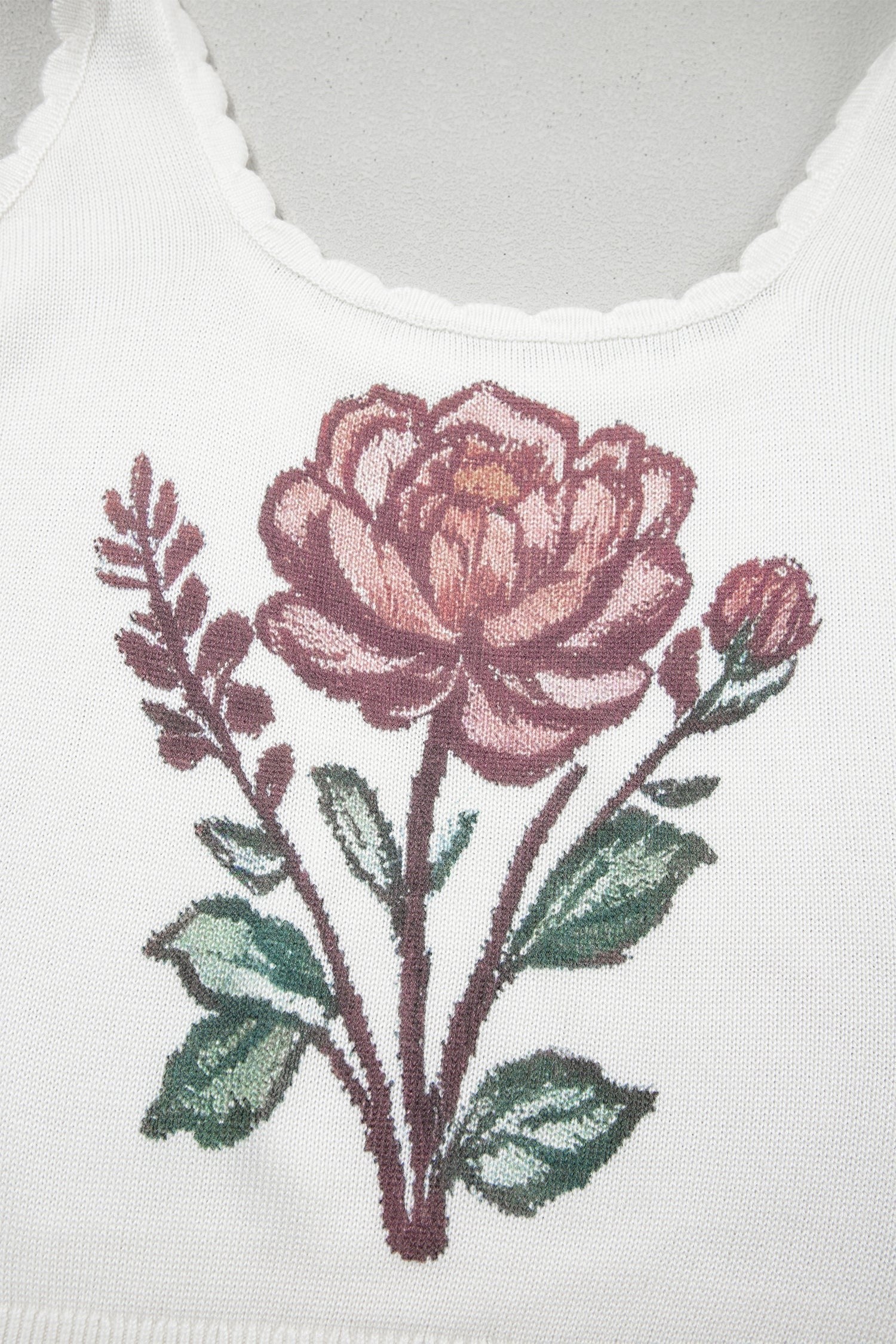 Doodlations Coffee Bar & Boutique white knit tank top featuring a detailed pink floral graphic and scalloped neckline.