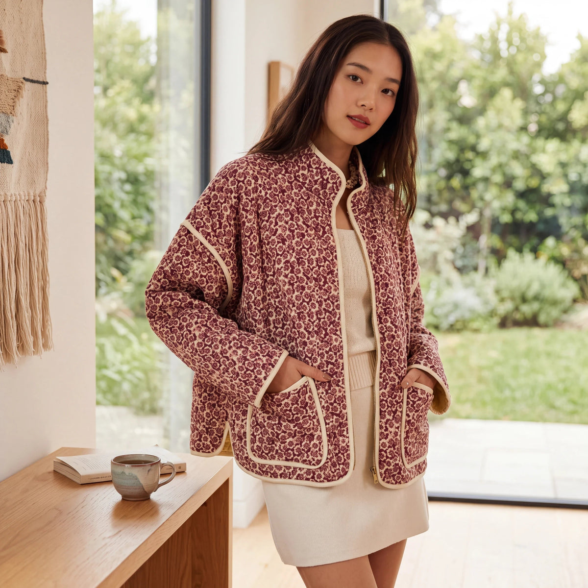 Doodlations Coffee Bar & Boutique floral quilted zip-up jacket with cream piping worn by a woman in a bright room.