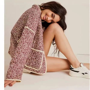 Doodlations Coffee Bar & Boutique floral quilted jacket with cream piping and patch pockets worn by a smiling woman