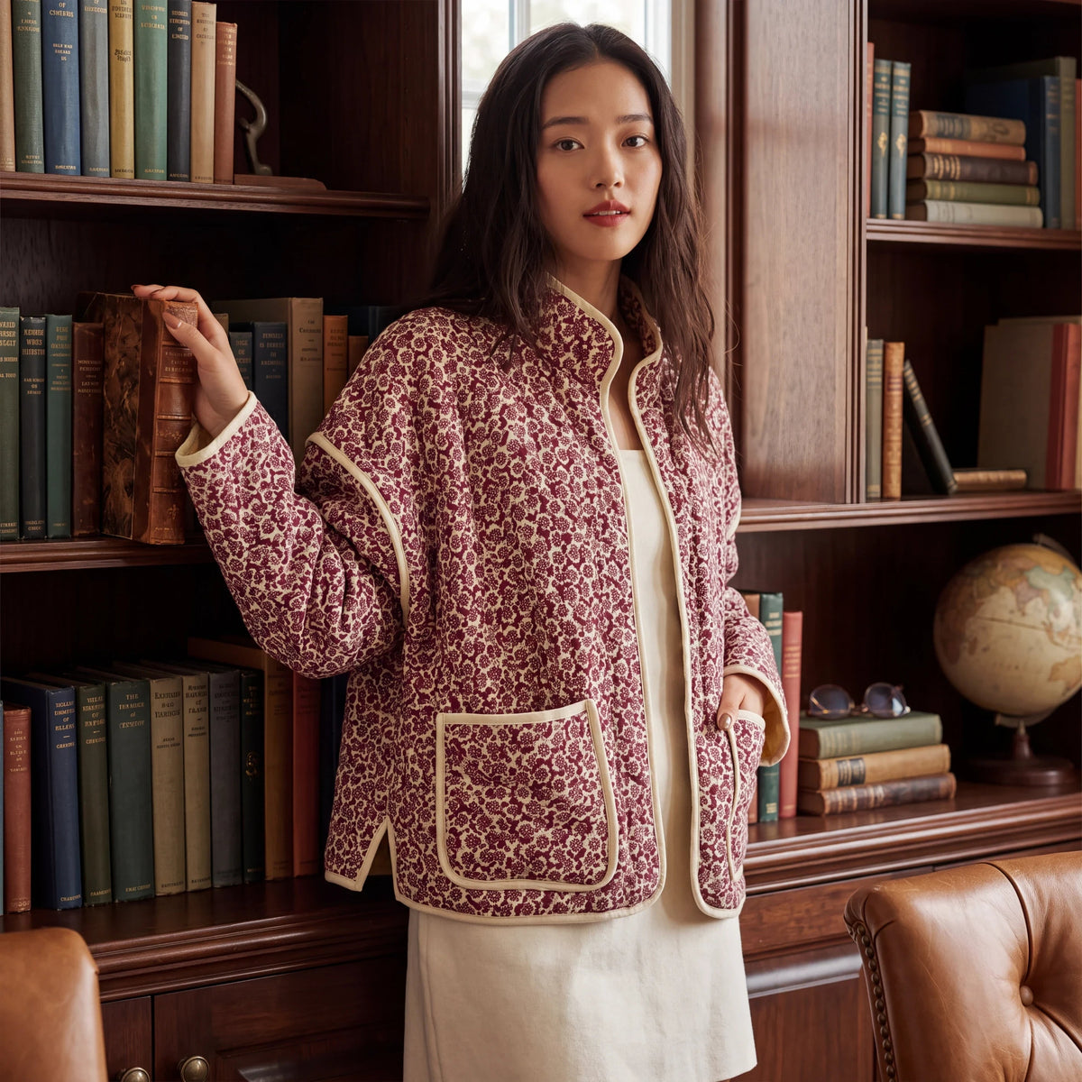 Doodlations Coffee Bar & Boutique floral quilted zip-up jacket with cream piping, worn by a woman in a library.