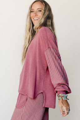 Doodlations Coffee Bar & Boutique fuchsia long sleeve top with raw seams and striped sleeves on a smiling woman