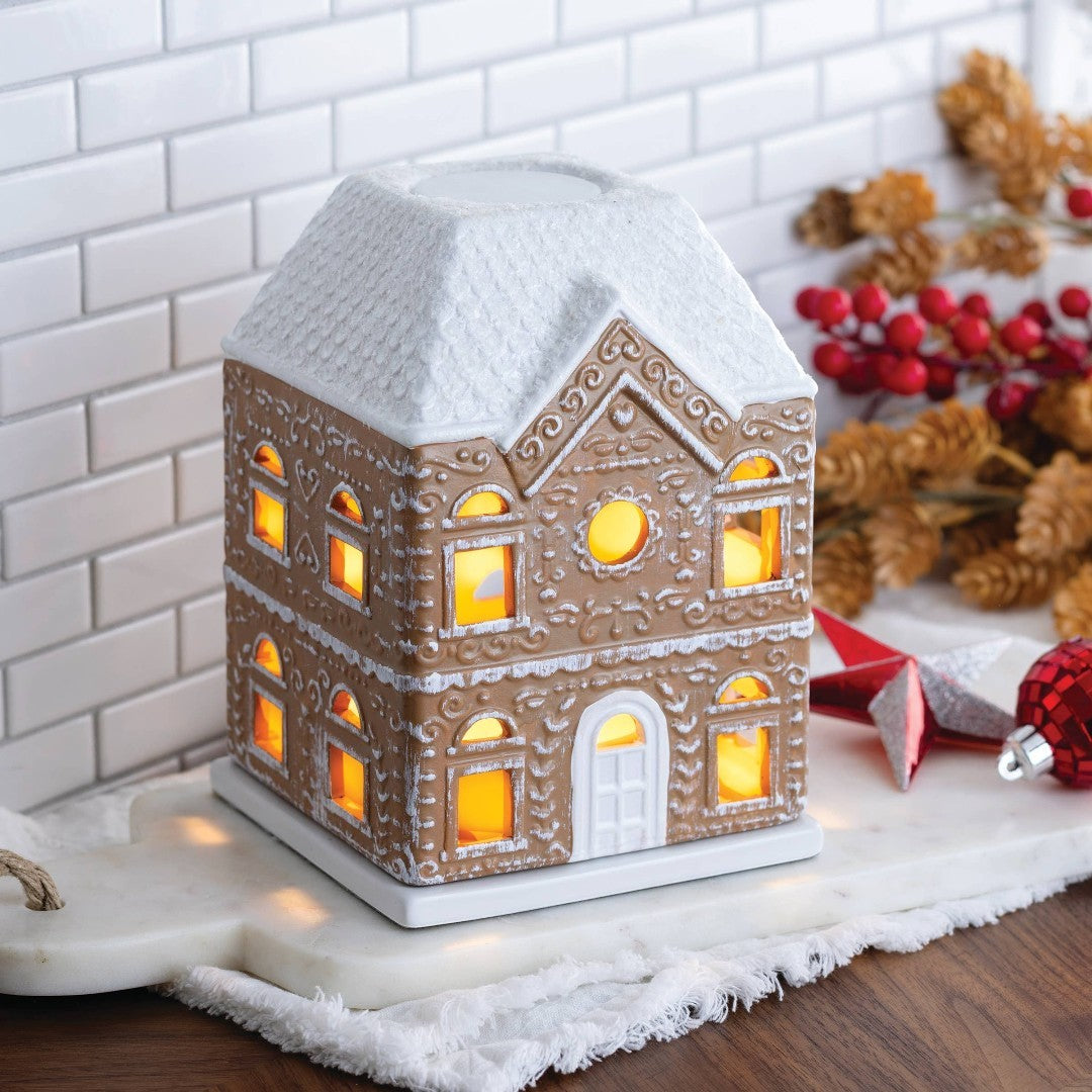 Doodlations Coffee Bar & Boutique Gingerbread House Fragrance Warmer with white roof and illuminated windows.