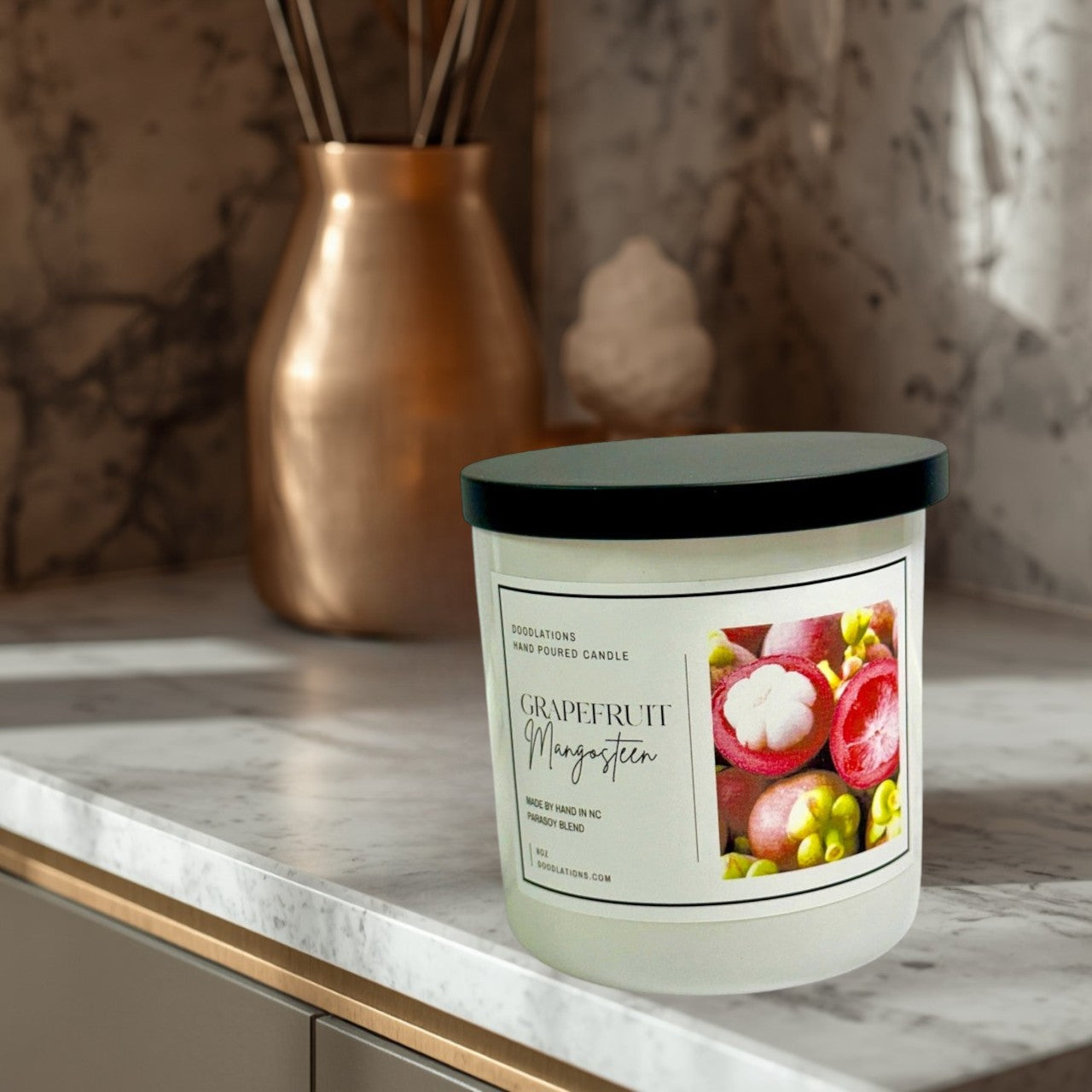 Doodlations Coffee Bar & Boutique Grapefruit & Mangosteen hand-poured candle in a white jar with a black lid. Features a label with fruit imagery.