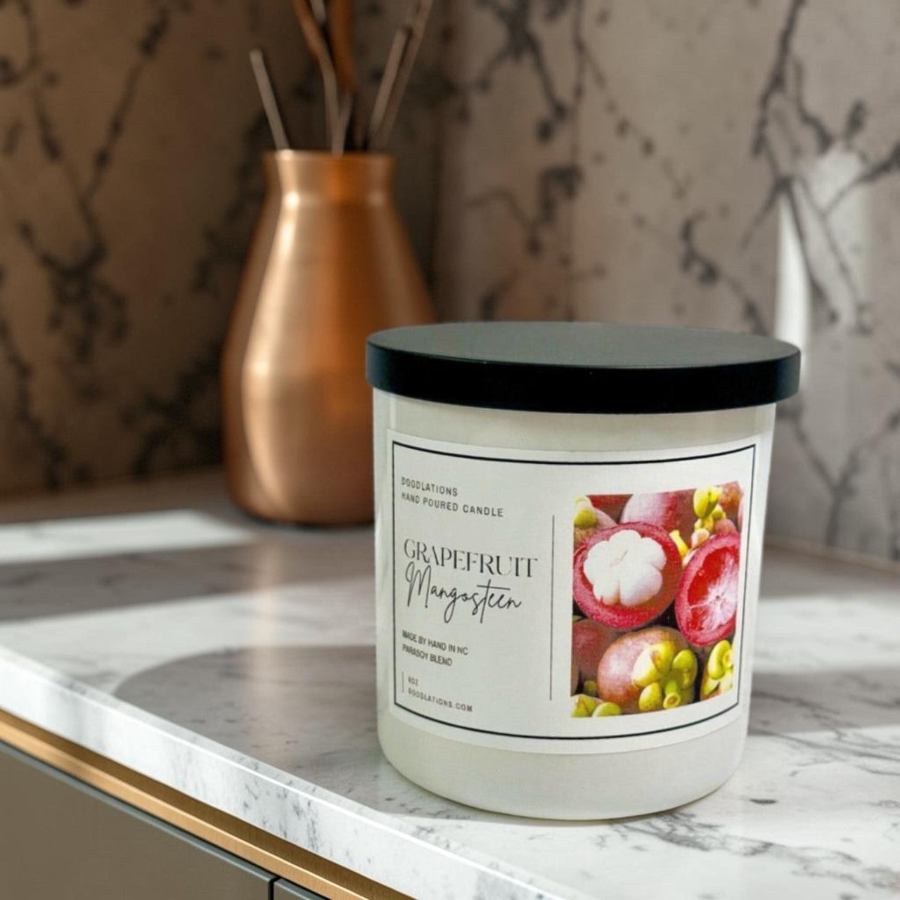 Doodlations Coffee Bar & Boutique Grapefruit & Mangosteen hand-poured candle in a white jar with a black lid. Features a label with fruit imagery.