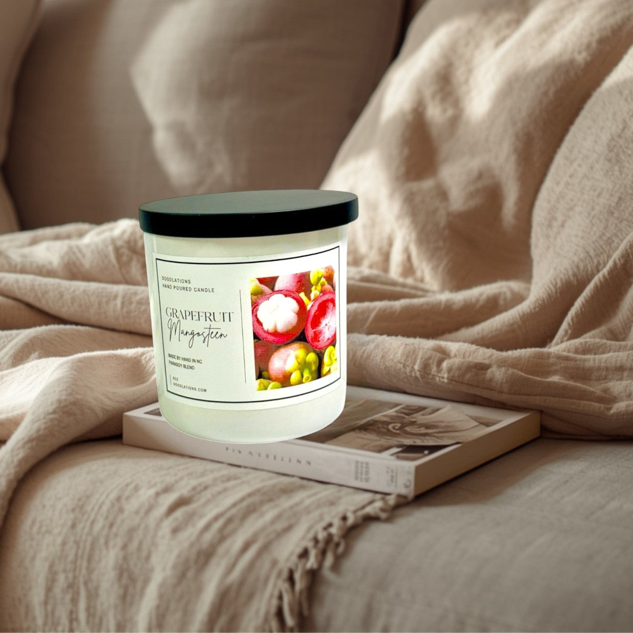 Doodlations Coffee Bar & Boutique Grapefruit & Mangosteen hand-poured candle in a white jar with a black lid. Features a label with fruit imagery.