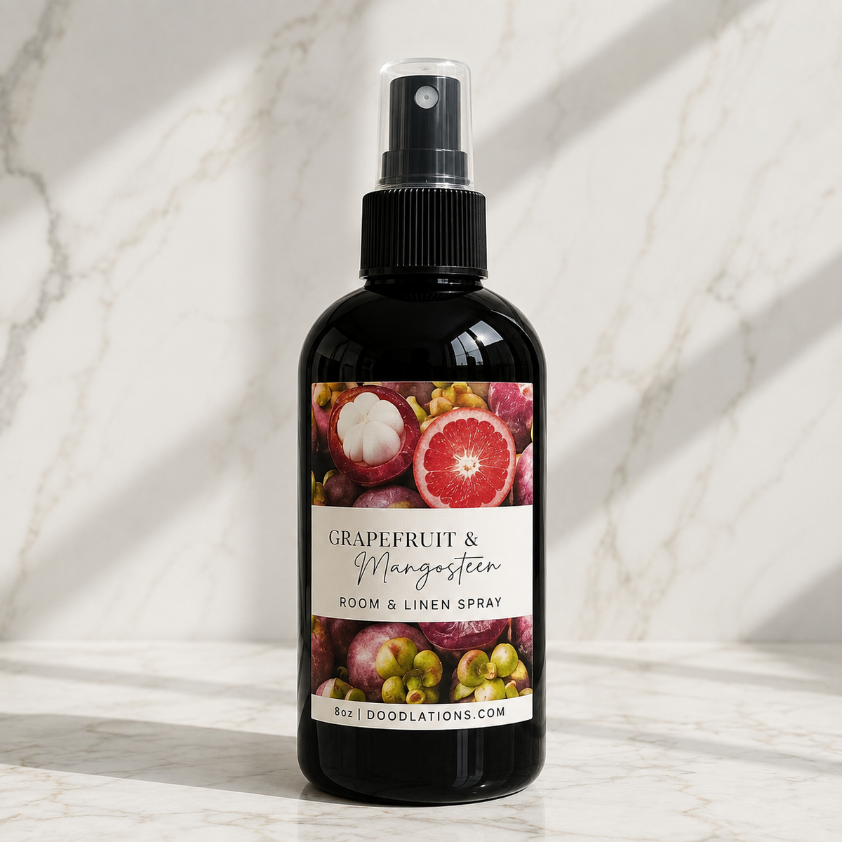 Doodlations Coffee Bar & Boutique Grapefruit & Mangosteen room and linen spray in an 8oz black bottle on marble.
