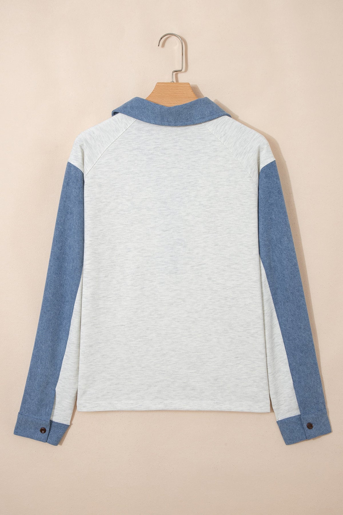 Doodlations Coffee Bar & Boutique light grey and blue denim patchwork long sleeve polo top on a hanger