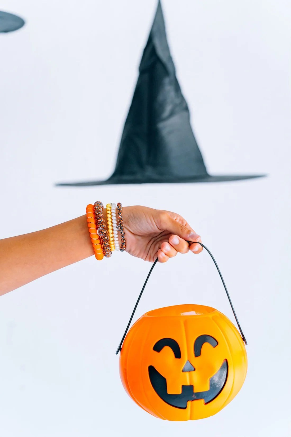 Doodlations Coffee Bar & Boutique Halloween hair tie set worn as bracelets with a pumpkin bucket