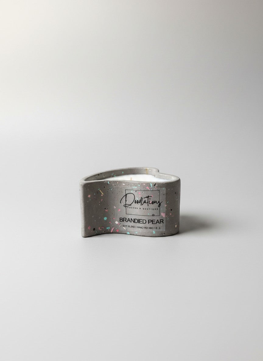Doodlations Coffee Bar & Boutique grey concrete heart-shaped candle with colorful speckles, "Brandied Pear" scent.