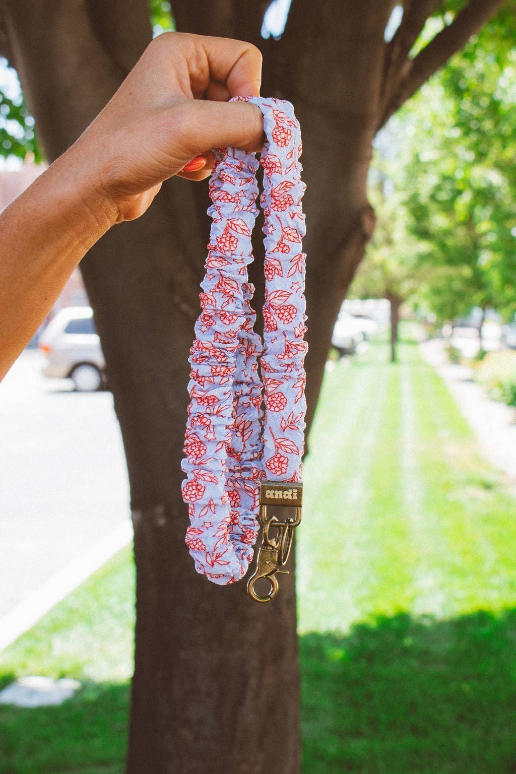 Doodlations Coffee Bar & Boutique hydrangea floral lanyard in red, white, and blue fabric with a gold metal clasp.