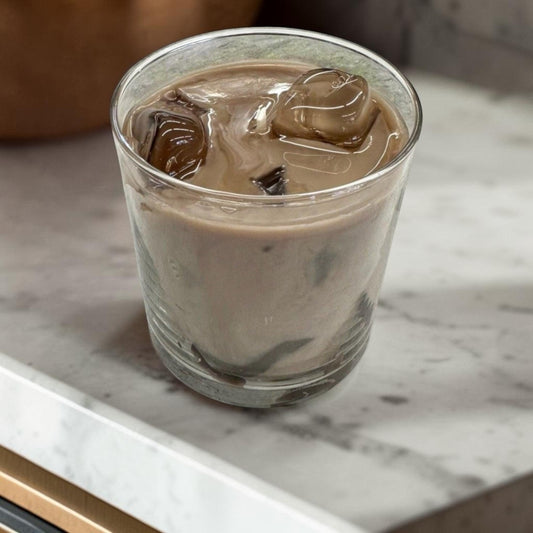 Doodlations Coffee Bar & Boutique Iced Hazelnut & Crème Coffee candle with coffee beans on a wooden surface.