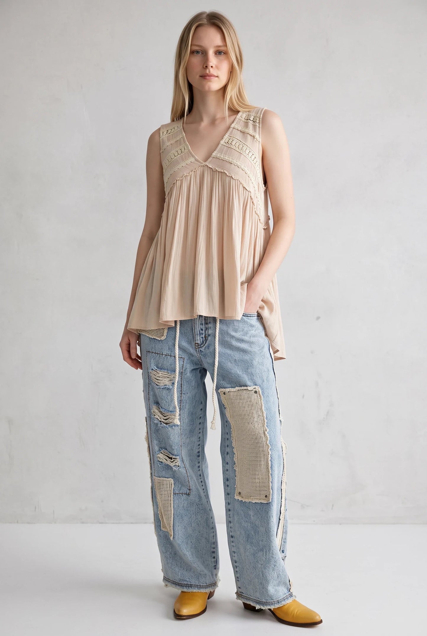Model wearing a Doodlations Coffee Bar & Boutique ivory sleeveless V-neck tank top with lace trim and flowy fit.