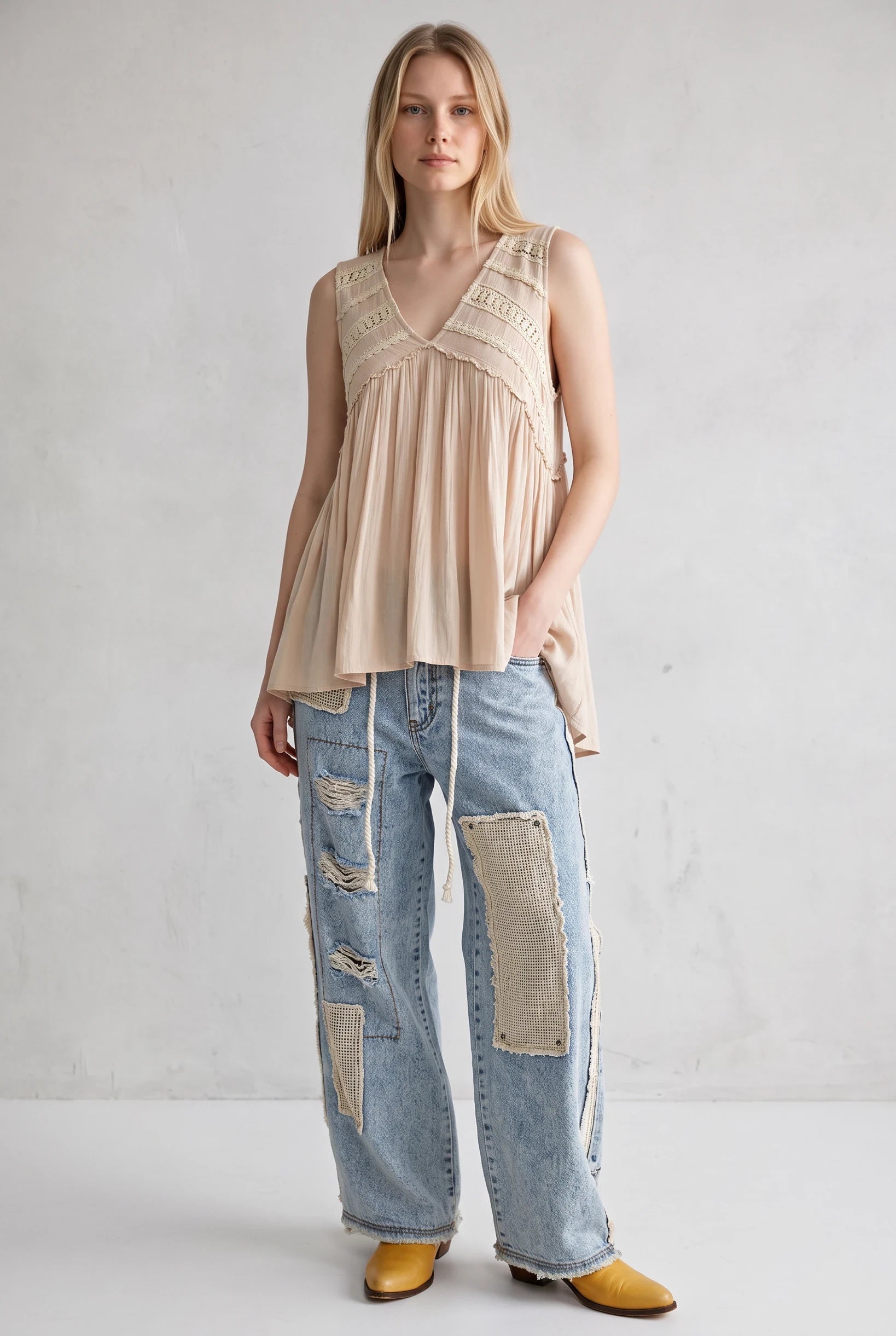 Model wearing a Doodlations Coffee Bar & Boutique ivory sleeveless V-neck tank top with lace trim and flowy fit.