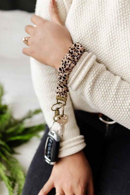Doodlations Coffee Bar & Boutique apricot terracotta jungle cat print fabric keychain worn on a wrist