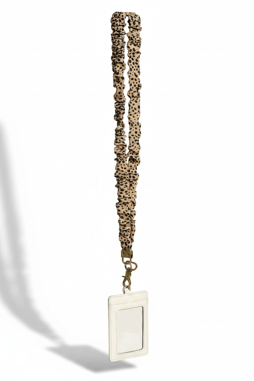 Doodlations Coffee Bar & Boutique jungle cat print fabric lanyard with a white ID badge holder and brass hardware.