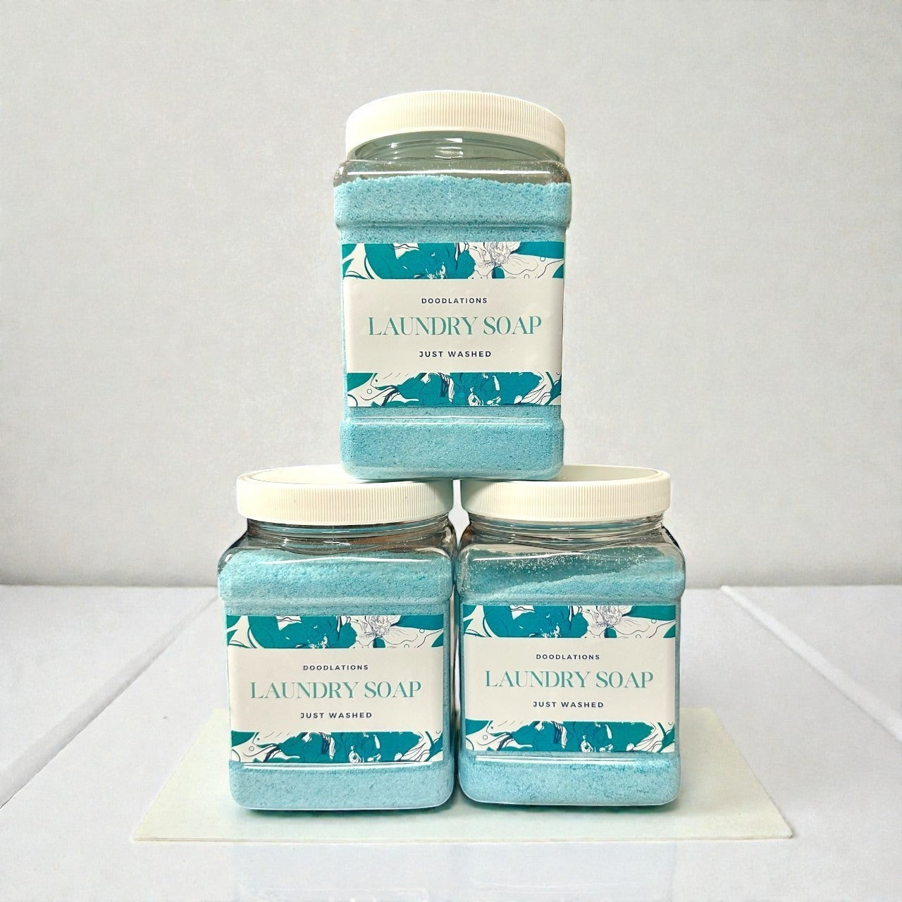 Doodlations Coffee Bar & Boutique Just Washed powdered laundry detergent in clear jars with blue powder.