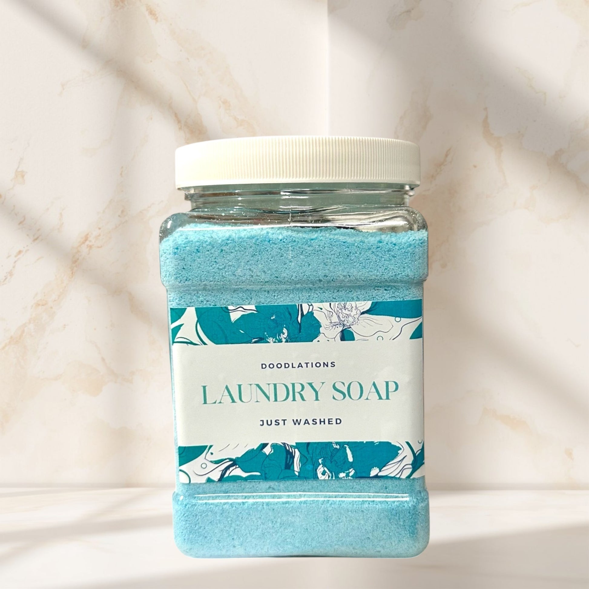 Doodlations Coffee Bar & Boutique Just Washed powdered laundry soap in a clear jar with a blue floral label.