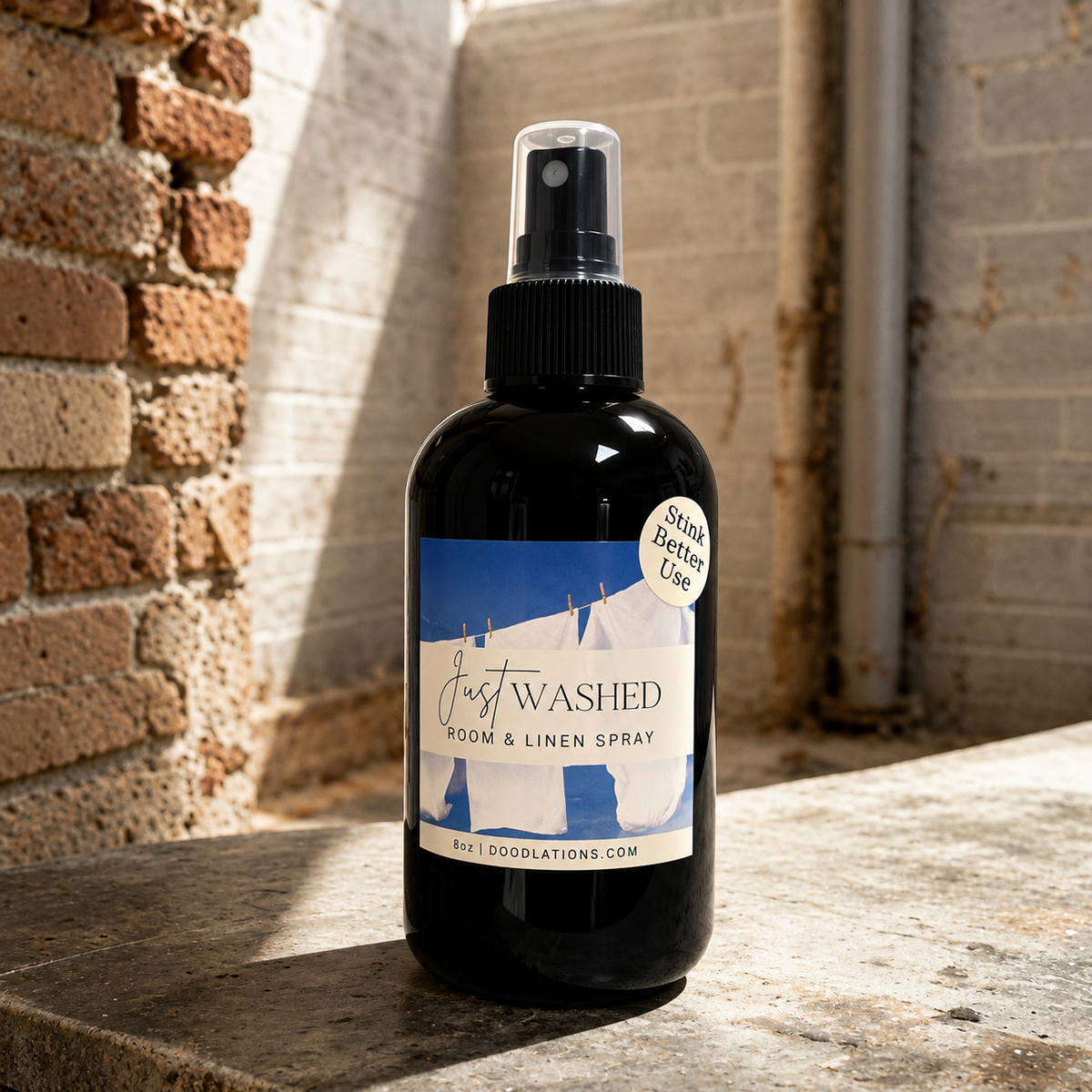 Doodlations Coffee Bar & Boutique Just Washed room and linen spray in a black bottle with a laundry-themed label.