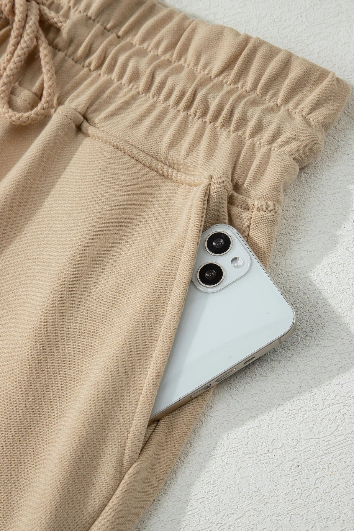 Doodlations Coffee Bar & Boutique khaki drawstring lounge pants featuring a deep side pocket holding a smartphone