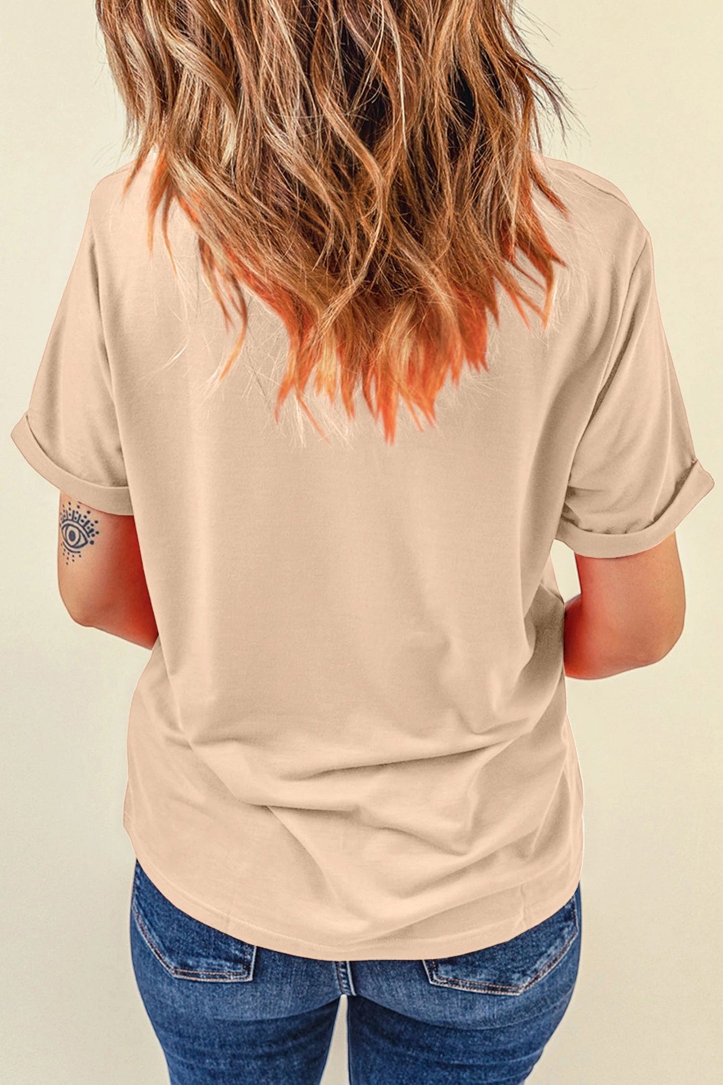 Woman wearing a plain khaki Doodlations Coffee Bar & Boutique crewneck t-shirt with rolled sleeves, back view.
