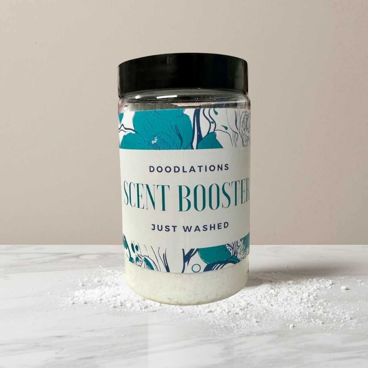 Doodlations Coffee Bar & Boutique Just Washed scent booster in a clear jar with a black lid. The label has floral designs and reads "DOODLATIONS SCENT BOOSTER JUST WASHED".