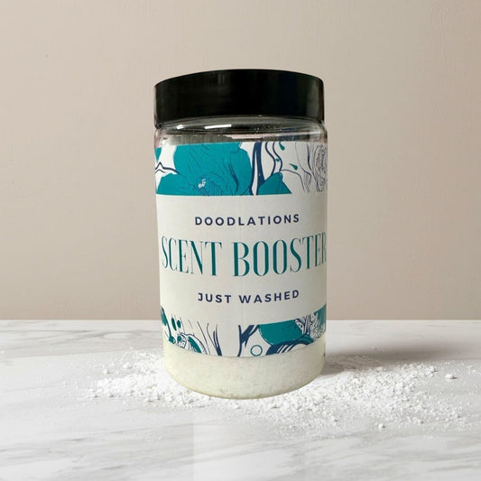 Doodlations Coffee Bar & Boutique Just Washed scent booster in a clear jar with a black lid. The label has floral designs and reads "DOODLATIONS SCENT BOOSTER JUST WASHED".