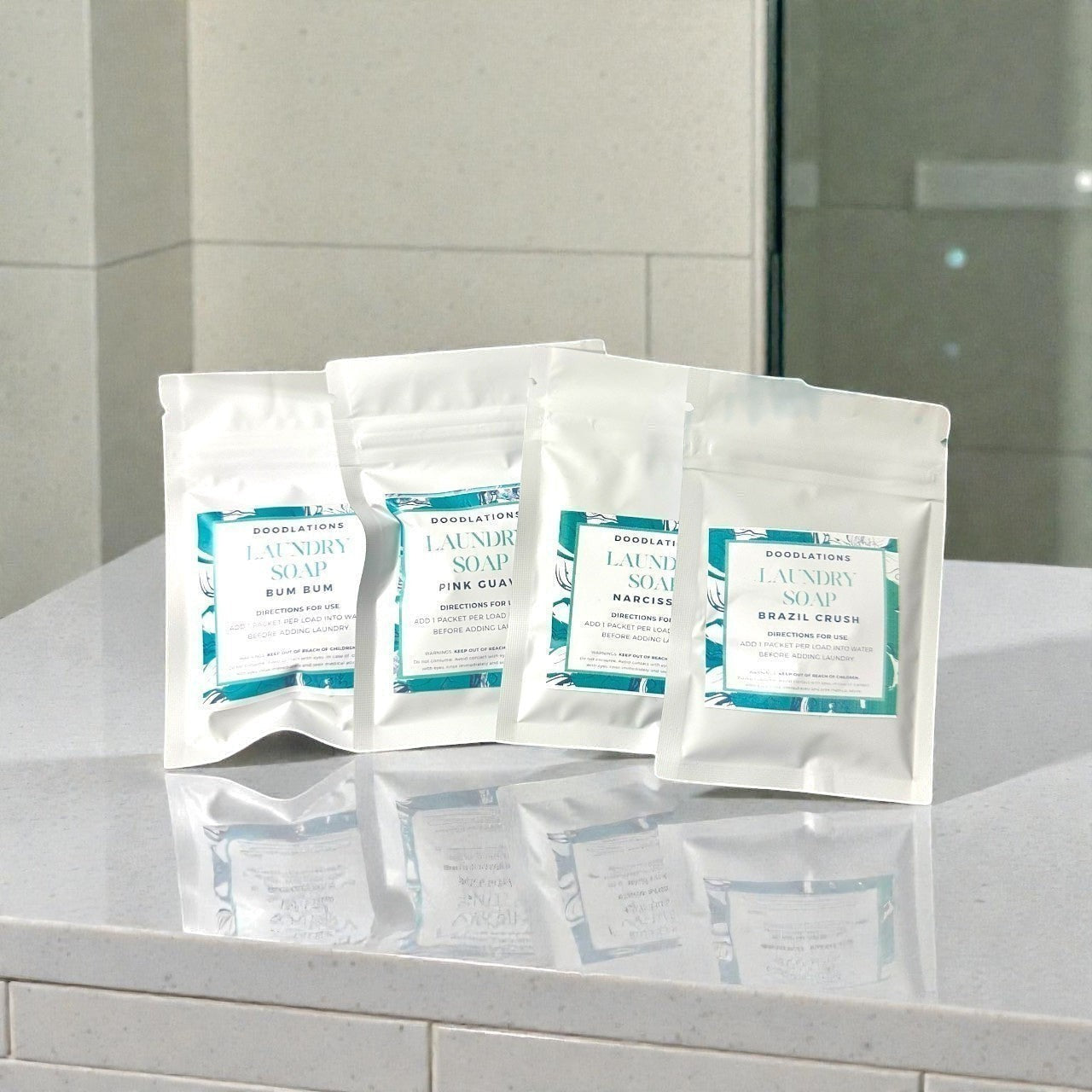 Doodlations Coffee Bar & Boutique laundry soap sampler with four 1oz packets: Bum Bum, Pink Guava, Narciss, and Brazil Crush scents.