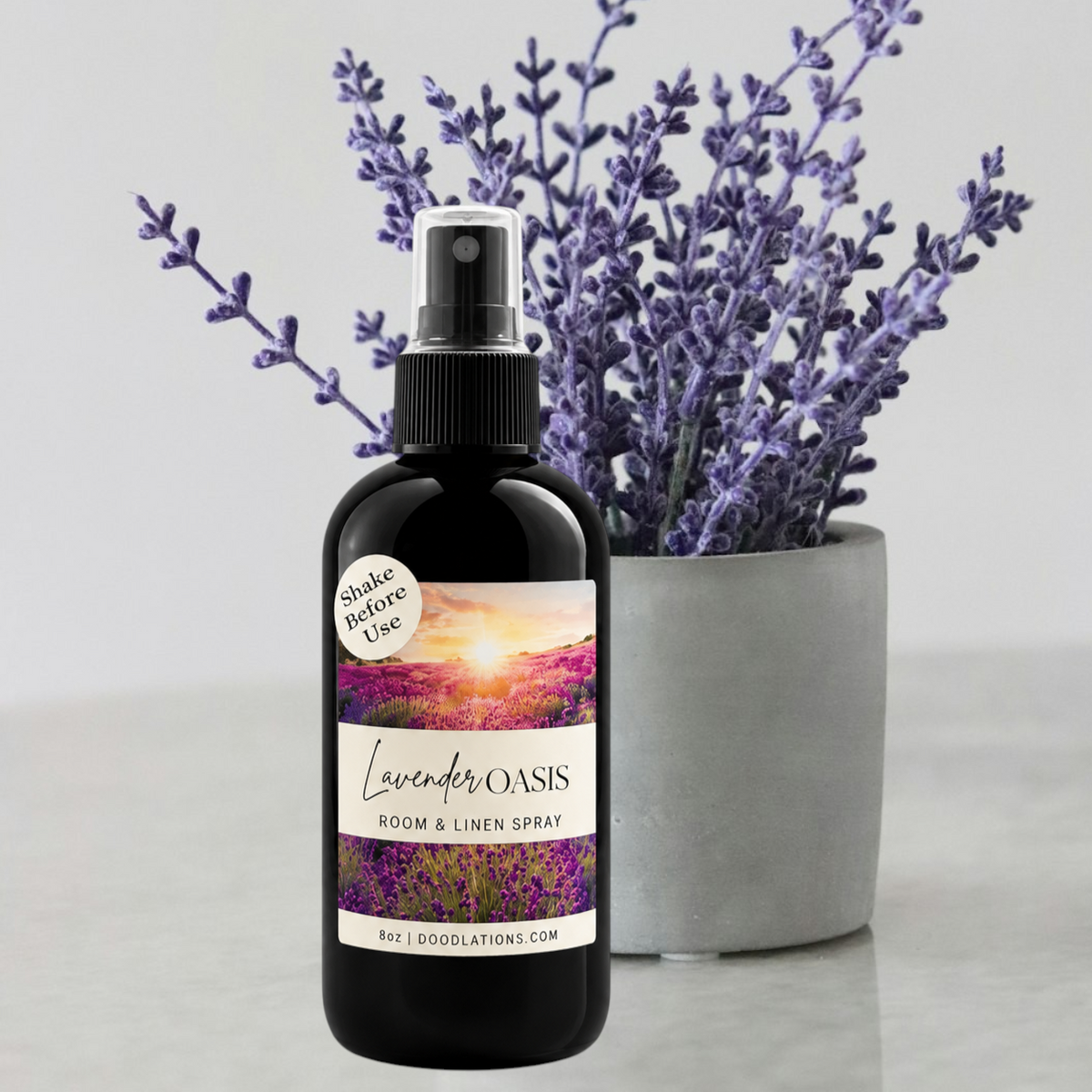 Doodlations Coffee Bar & Boutique Lavender Oasis room and linen spray in a black bottle with a lavender plant background
