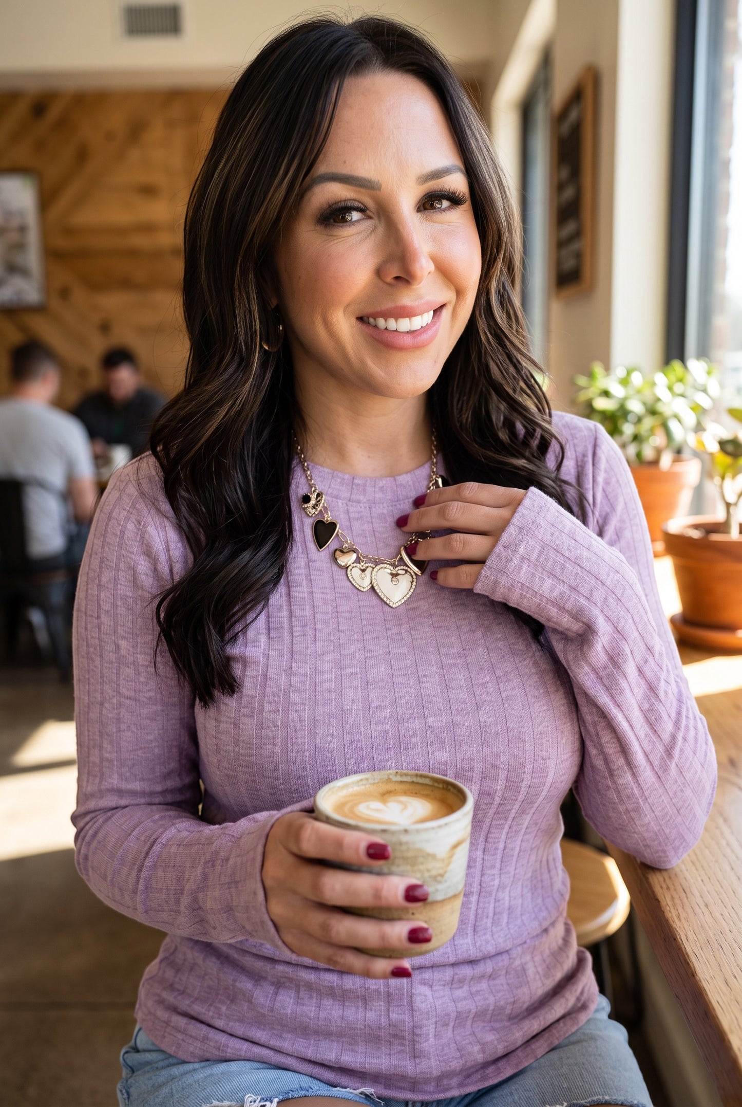 Woman wearing a lavender ribbed long sleeve top by Doodlations Coffee Bar & Boutique while holding a coffee cup