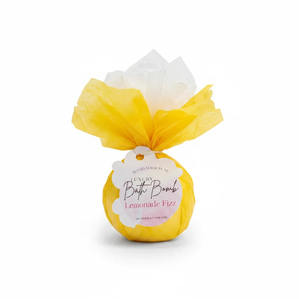 Doodlations Coffee Bar & Boutique Lemonade Fizz bath bomb wrapped in bright yellow tissue paper with a product tag.