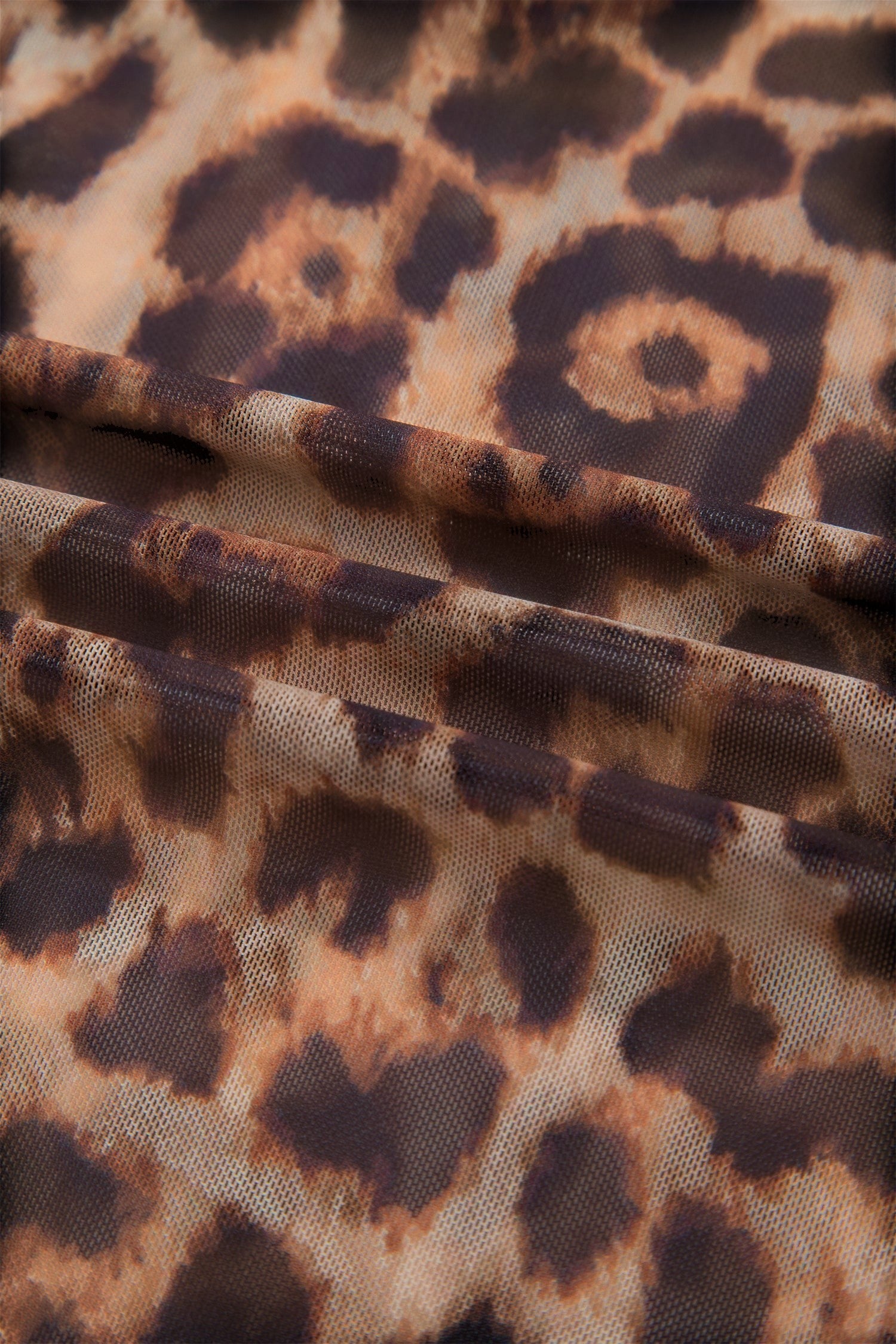 Doodlations Coffee Bar & Boutique leopard print mesh fabric close-up showing semi-sheer texture and earthy tones.
