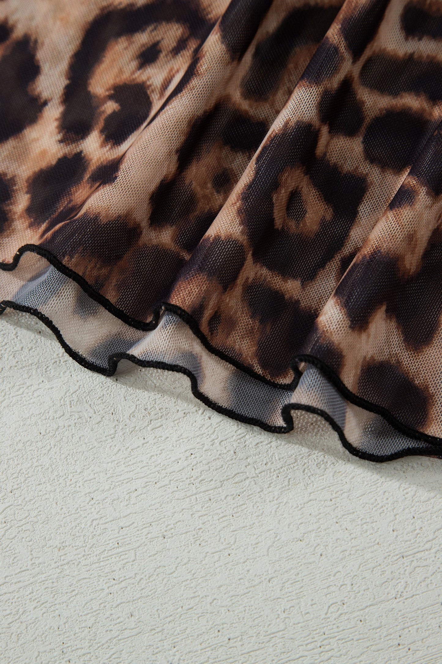 Doodlations Coffee Bar & Boutique leopard print mesh top with a delicate black lettuce-edge hem detail.