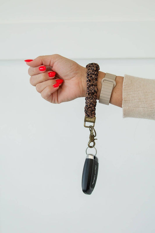 Doodlations Coffee Bar & Boutique leopard print scrunchie keychain worn on a wrist with a car key fob