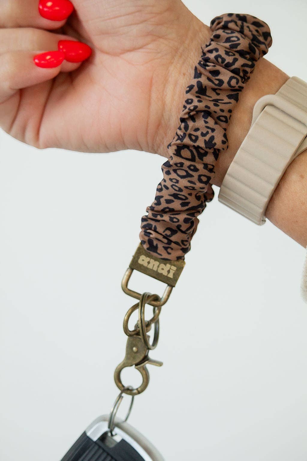 Doodlations Coffee Bar & Boutique leopard print fabric scrunchie keychain worn on a wrist with antique brass hardware