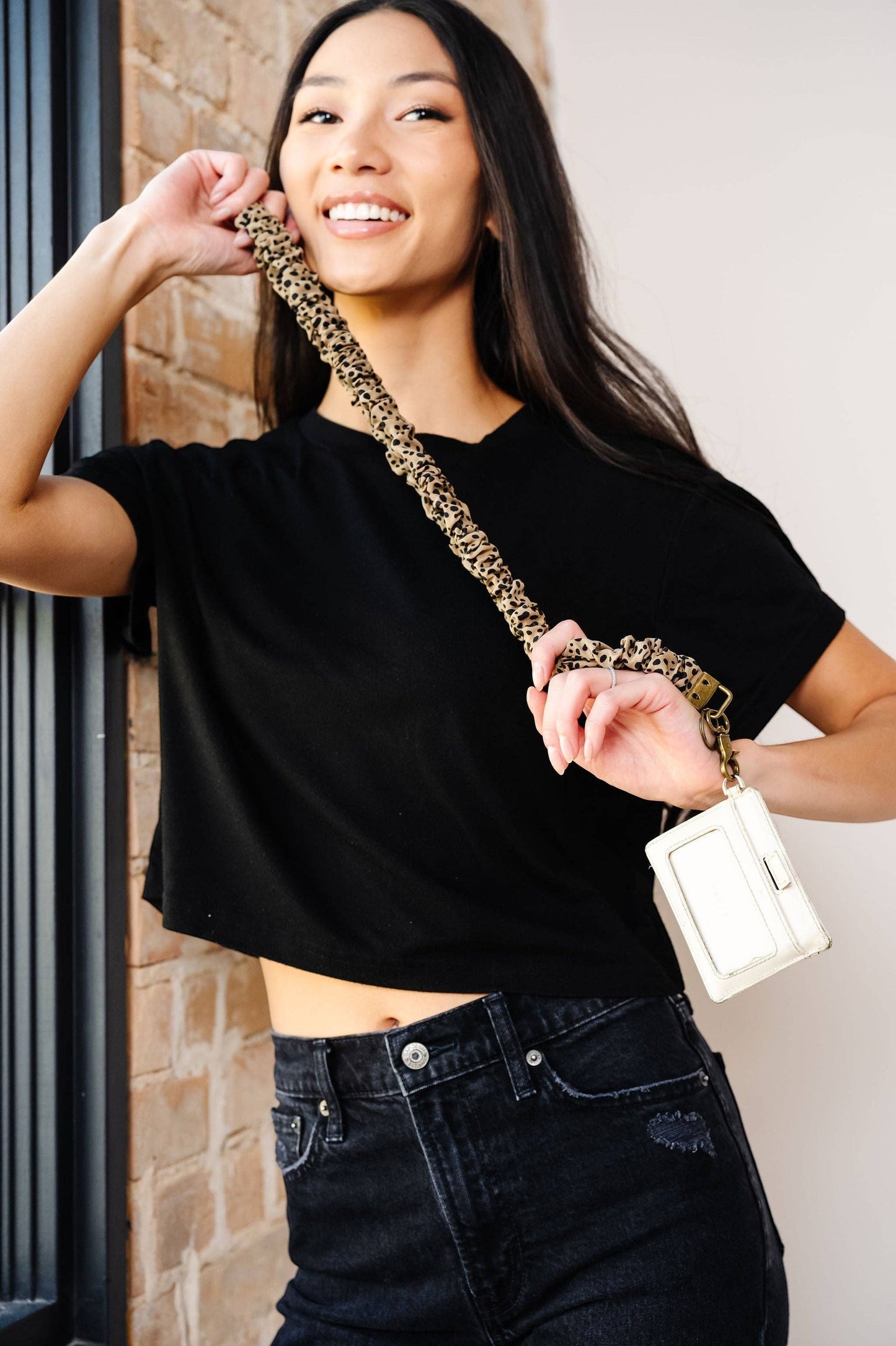 Doodlations Coffee Bar & Boutique leopard print scrunchie lanyard with antique-brass hardware worn by a smiling woman