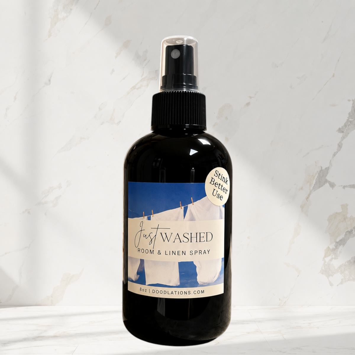 Doodlations Coffee Bar & Boutique Just Washed room and linen spray in a black bottle with a laundry-themed label.